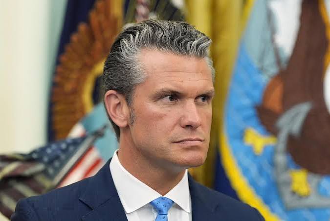 Secretary of War Pete Hegseth in front of military flags, whose department designated Anthropic a supply chain risk