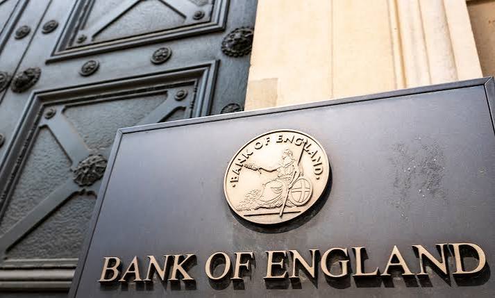 A brass Bank of England sign with the seated Britannia emblem mounted on the central bank's building