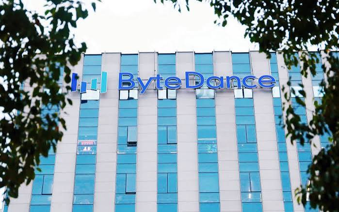 ByteDance logo on the glass facade of a ByteDance office building framed by tree branches