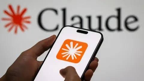 Claude app icon on a smartphone held in front of the red Claude logo on a white background