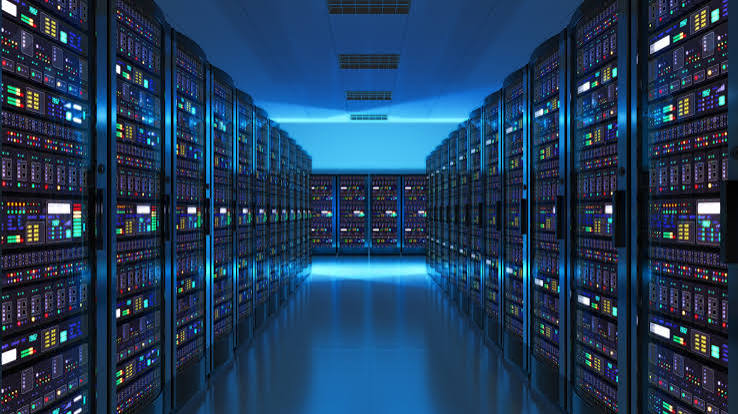 Long aisle of server racks with glowing status lights in a blue-lit data center