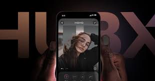 A hand holds a phone running a HubX photo app, with the HUBX wordmark on a dark background