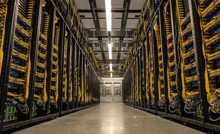 Long aisle of server racks with dense yellow fiber cabling inside a Meta AI data center
