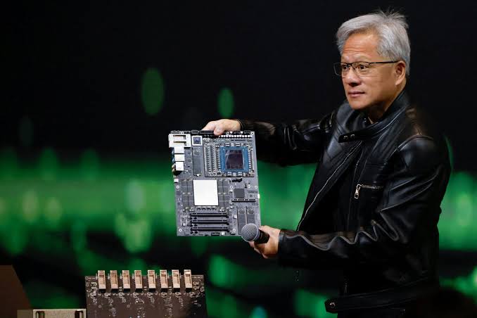 Nvidia chief executive Jensen Huang holds up an AI accelerator board on stage, wearing his signature black leather jacket