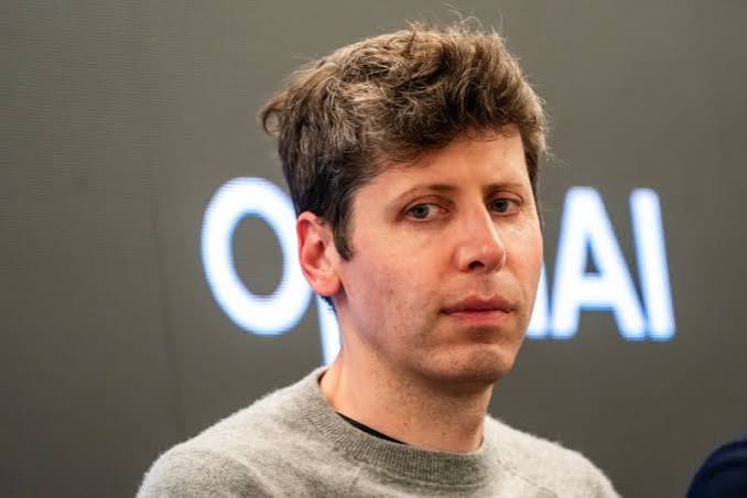 Sam Altman in a grey sweater in front of an illuminated OpenAI wordmark on a dark wall, as OpenAI seeks $30 billion at a reported $1.4 trillion valuation