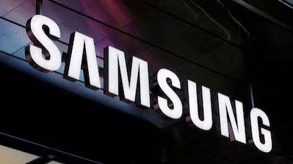 Illuminated white Samsung logo lettering on the dark glass facade of a building