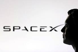 Silhouette of a person against the SpaceX wordmark in low light