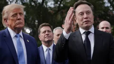 President Donald Trump stands outdoors beside Director of National Intelligence Jay Clayton and Elon Musk
