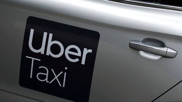 An Uber driver checking a smartphone that shows a blocked ride-hailing account