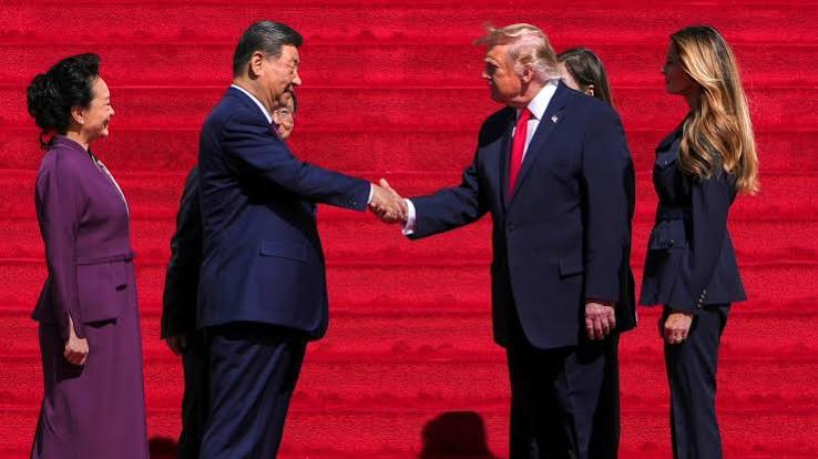 Chinese President Xi Jinping and US President Donald Trump shake hands in front of a red backdrop as Peng Liyuan and Melania Trump look on