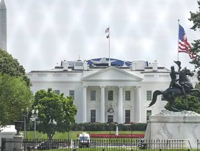 The north facade of the White House in Washington with US flags flying and the Andrew Jackson statue in Lafayette Square in the foreground