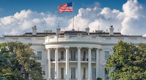 The White House south facade under a blue sky with the US flag flying